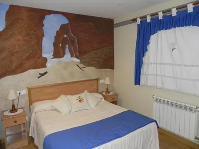 a bedroom with a bed with a painting on the wall at O Lar de Carmiña in Devesa