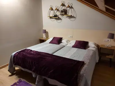 a bedroom with a large bed and a chandelier at Ultreia in Portomarin