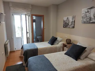 a hotel room with two beds and a window at Ultreia in Portomarin