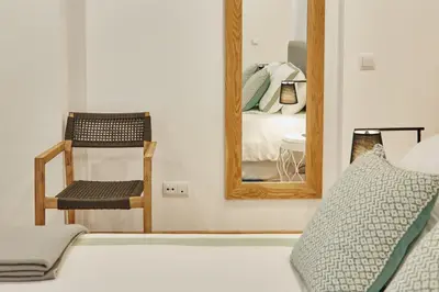 a bedroom with a mirror and a chair and a bed at Apartamentos Orfas in Santiago de Compostela