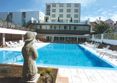 a swimming pool with a statue next to a building at Apartamentos Sarga Sentirgalicia in Cabañas