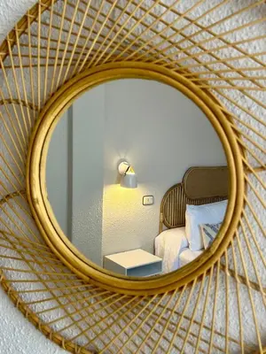 a mirror reflecting a bedroom with a bed and a table at Apartamentos Sarga Sentirgalicia in Cabañas