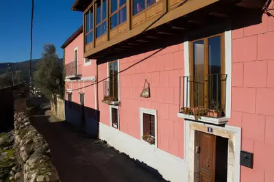 a pink building with a balcony on the side of it at CASA CASTAÑÉ in Puente de Domingo Flórez