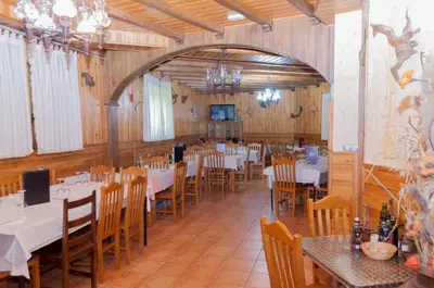 a dining room with tables and chairs and a chandelier at Hostal Tribal in Puebla de Sanabria