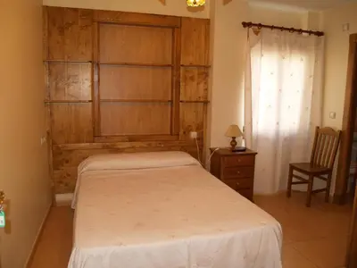 a bedroom with a bed and a wooden wall at Hostal Tribal in Puebla de Sanabria