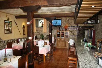 a restaurant with tables and chairs in a room at Hostal Tribal in Puebla de Sanabria