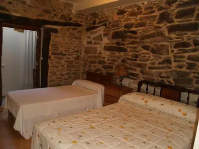 two beds in a room with a stone wall at Hostal Tribal in Puebla de Sanabria