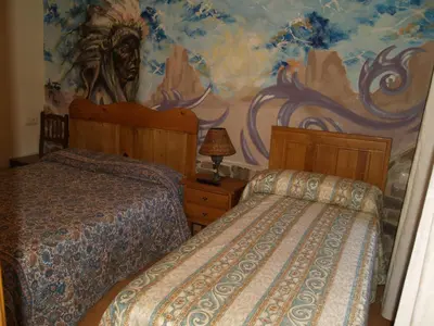 a bedroom with two beds and a painting on the wall at Hostal Tribal in Puebla de Sanabria