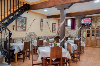 a restaurant with tables and chairs and a staircase at Hostal Tribal in Puebla de Sanabria