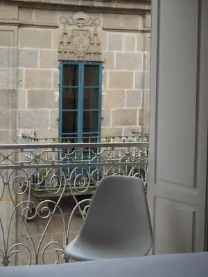 a chair sitting on a balcony in front of a building at Libredón Rooms in Santiago de Compostela
