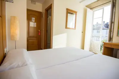 a white bathroom with a sink and a tub and a toilet at Libredón Rooms in Santiago de Compostela