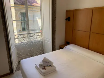 a bedroom with a bed and a balcony with a television at Libredón Rooms in Santiago de Compostela