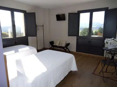 a bedroom with a large white bed and windows at Albergue Restaurante Casa Herminia in El Campiello