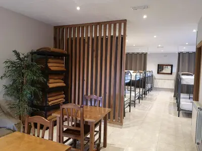a dining room with tables and chairs and a partition at Albergue Restaurante Casa Herminia in El Campiello