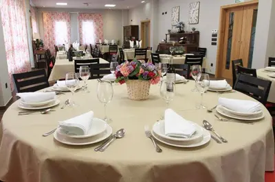 a table with white plates and napkins and wine glasses at Albergue Restaurante Casa Herminia in El Campiello