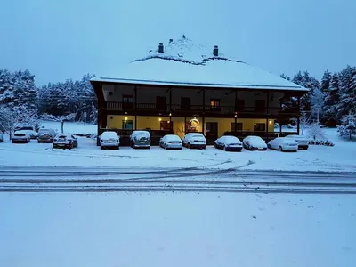 a snow covered building with cars parked in a parking lot at Complejo O Piñeiral A Fonsagrada in Fonsagrada