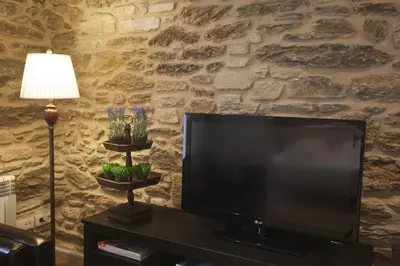 a flat screen tv in a living room with a stone wall at Catedral Site by Como en Casa in Santiago de Compostela