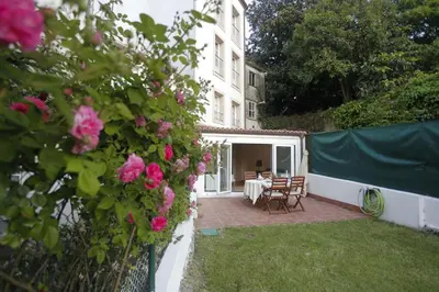a garden with a table and chairs and pink roses at Catedral Site by Como en Casa in Santiago de Compostela