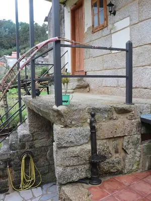a metal railing on a stone wall with a wooden door at Bodega rural tipo loft in Ourense