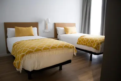 two beds sitting next to each other in a bedroom at Lux Apartamentos Rosalia in Santiago de Compostela