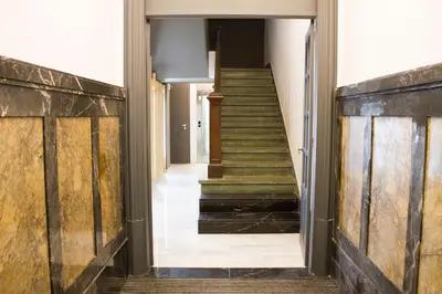 a hallway with stairs in a building with wooden doors at Lux Apartamentos Rosalia in Santiago de Compostela