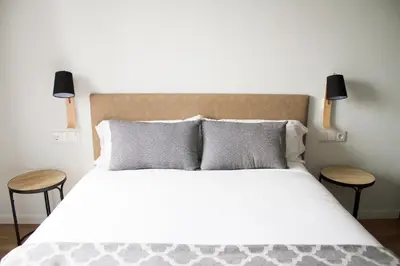 a bedroom with a large bed with two tables at Lux Apartamentos Rosalia in Santiago de Compostela