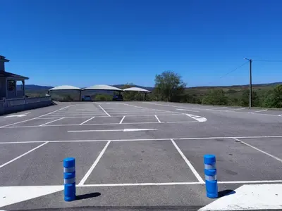 an empty parking lot with blue poles in it at Hotel Restaurante Cazador in Pereiro