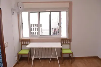 a table and two chairs in a room with a window at ArArAt Hostel in Santiago de Compostela