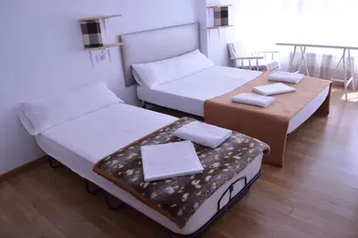 two beds and a table in a room at ArArAt Hostel in Santiago de Compostela
