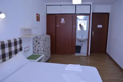 a bedroom with a bed and a bathroom with a sink at ArArAt Hostel in Santiago de Compostela
