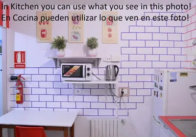 a kitchen with a microwave on a white tiled wall at ArArAt Hostel in Santiago de Compostela