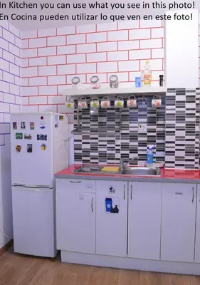 a kitchen with white appliances and a white brick wall at ArArAt Hostel in Santiago de Compostela