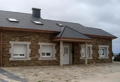 a brick house with white windows and a roof at Casa As Pedreiras in Barreiros
