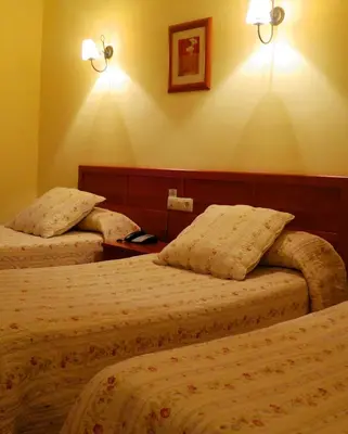 a hotel room with two beds and lights on the wall at Hotel Restaurante America in Oca