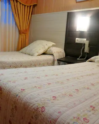 a hotel room with two beds and a lamp at Hotel Restaurante America in Oca