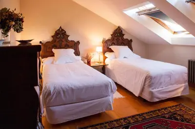 a bedroom with two beds with white sheets at Pazo de Brandeso & Country Club in Arzúa
