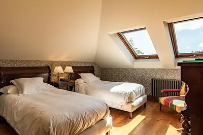 two beds in a room with two windows at Pazo de Brandeso & Country Club in Arzúa