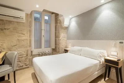 a bedroom with a large white bed and a desk at Hotel Praza Quintana in Santiago de Compostela