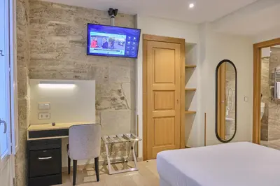 a bedroom with a bed and a desk and a tv on a wall at Hotel Praza Quintana in Santiago de Compostela