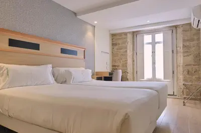 a bedroom with a large white bed and a desk at Hotel Praza Quintana in Santiago de Compostela