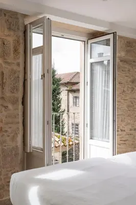 a bedroom with a bed and a large window at Hotel Praza Quintana in Santiago de Compostela