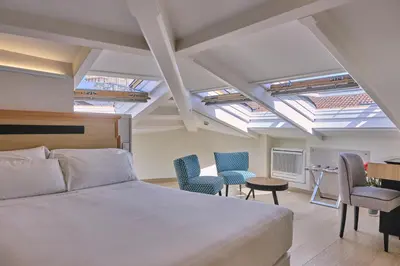 a bedroom with a bed and chairs and skylights at Hotel Praza Quintana in Santiago de Compostela