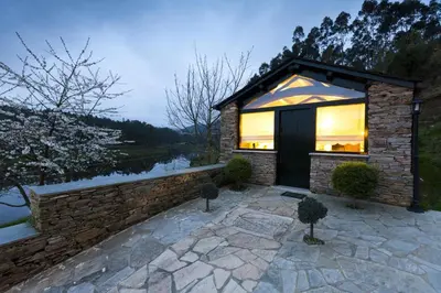 a house with a large window on a stone patio at Finca Goleta in Foz