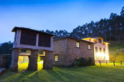 a stone house with a building on top of a field at Finca Goleta in Foz