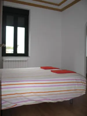 a bed in a white room with two windows at Casa Rural La Dama del Alba in Vega de Magaz