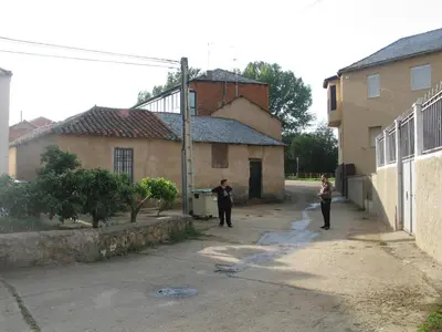 two people walking down a street next to a building at Casa Rural La Dama del Alba in Vega de Magaz