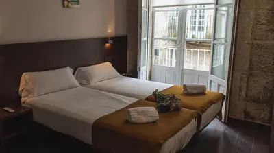 a bedroom with a bed with two towels and a window at Pensión A Casa do Peregrino in Santiago de Compostela