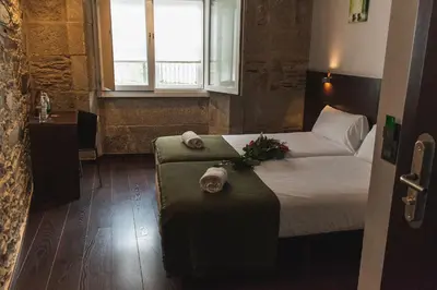a hotel room with a bed and a bench with flowers at Pensión A Casa do Peregrino in Santiago de Compostela