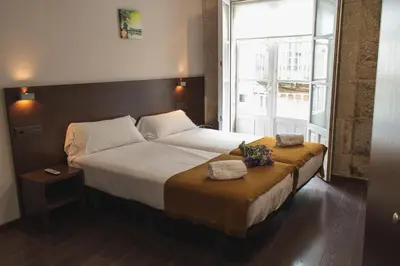 a bedroom with a large bed with flowers on it at Pensión A Casa do Peregrino in Santiago de Compostela