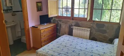 a bedroom with a bed and a stone wall at Hotel Rural Camino Medulas in Ponferrada